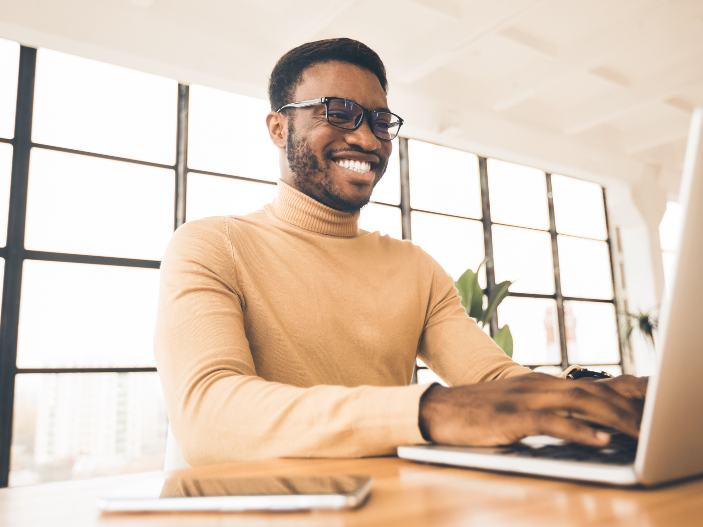 Smiling professional working on a laptop in a bright office, symbolizing strategic use of sustainability reporting for CSRD compliance.