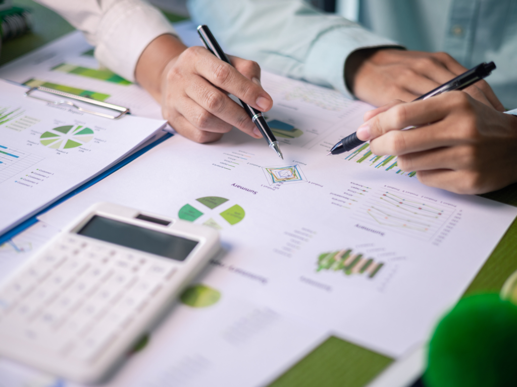 Two professionals analyzing sustainability reports with charts and graphs, symbolizing collaborative efforts in data-driven decision-making.
